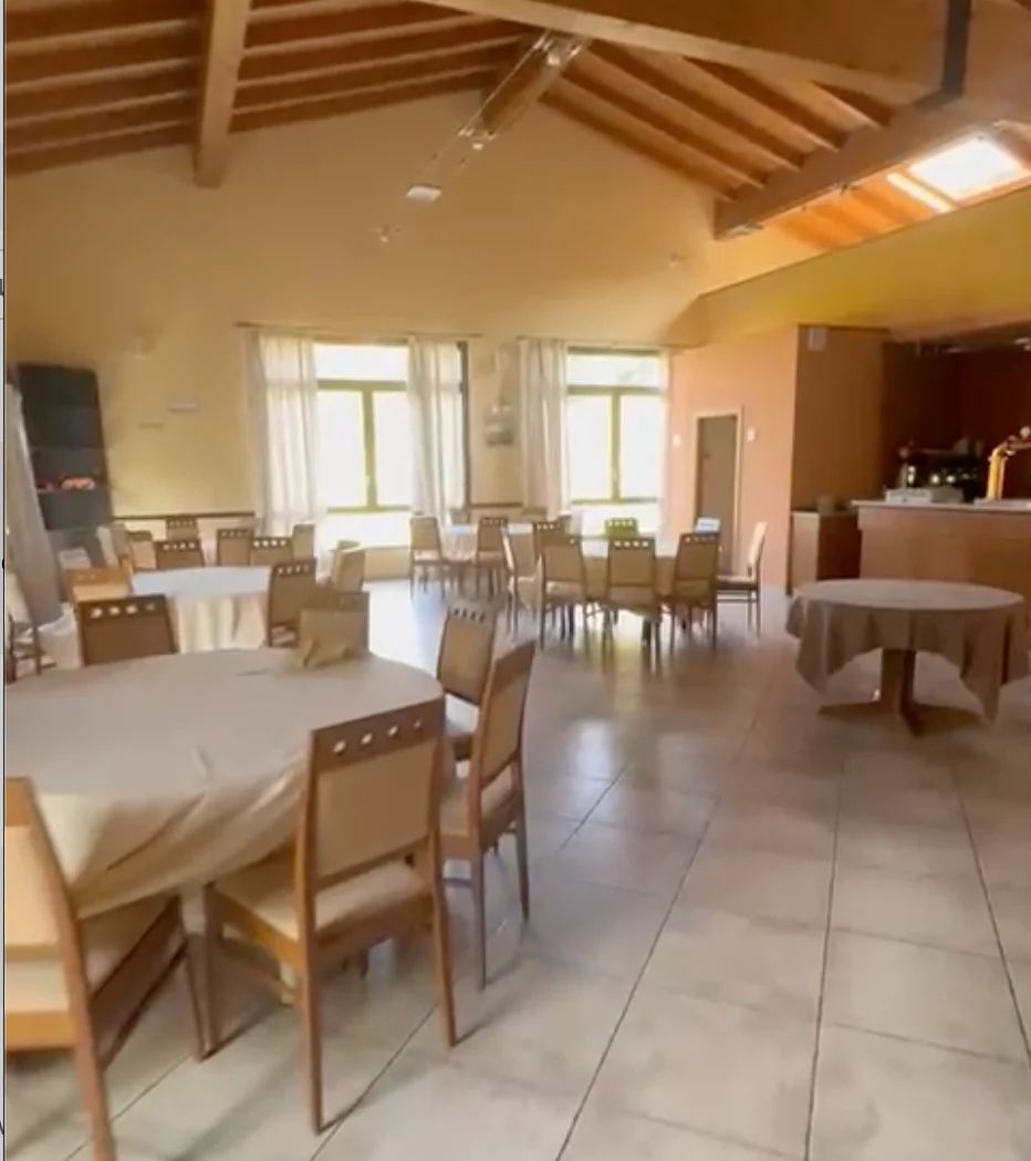 Sala con travi a vista e tavoli rotondi